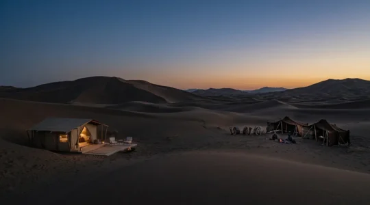 Contraste entre un bivouac de luxe et un campement nomade dans les dunes du désert sous un ciel étoilé