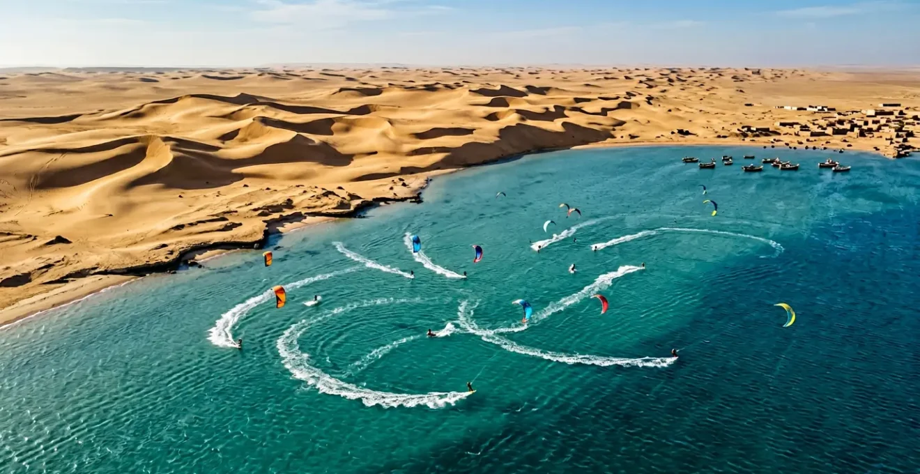 Vue aérienne d'une lagune turquoise avec kitesurfers naviguant entre désert et océan