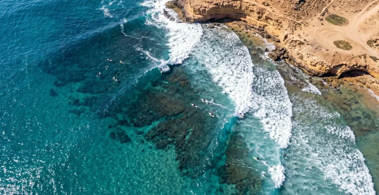 Vue aérienne d'un point break avec surfeurs positionnés selon la hiérarchie du line-up