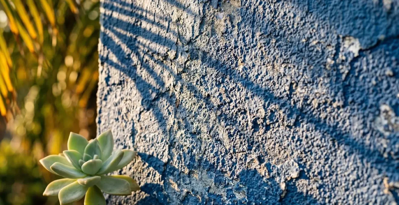 Mur bleu Majorelle baigné par la lumière dorée du soleil couchant avec ombres de palmiers