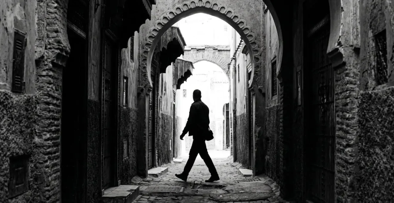 Silhouette d'un marcheur déterminé dans une ruelle de la médina avec jeu d'ombres et lumières